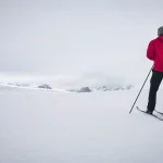 Skifahrer mit roter Jacke in den Bergen im Winter. Rondane-Nationalpark in Norwegen.
