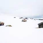Holzhütten im Freien in schönen schneebedeckten Bergen und nebligen Landschaft im Hintergrund. Architektur und Jahreszeit Konzept. Von Rondane Nationalpark in Norwegen.